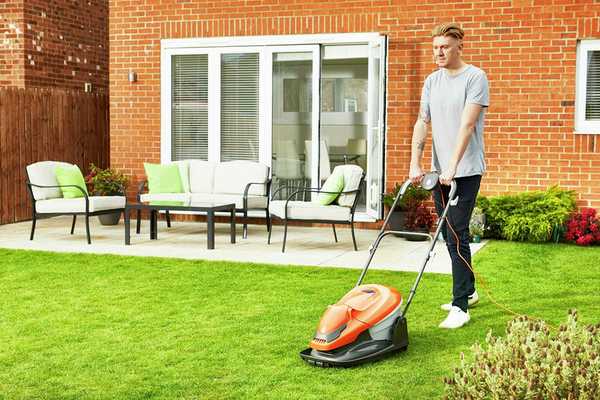 A man mowing a lawn with a Flymo EasiGlide hover lawnmower.
